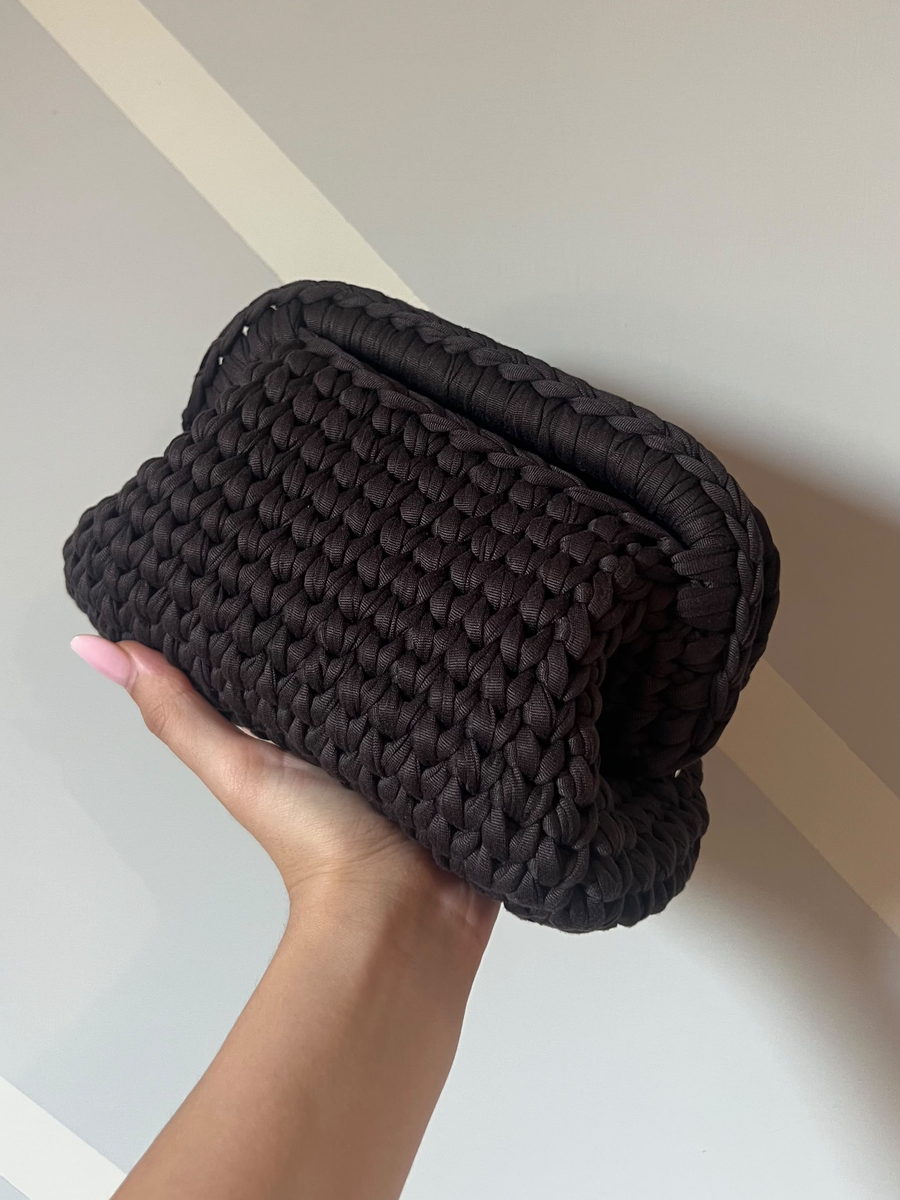 La pouch capiente Cacao in filato cioccolato opaco, tenuta in mano